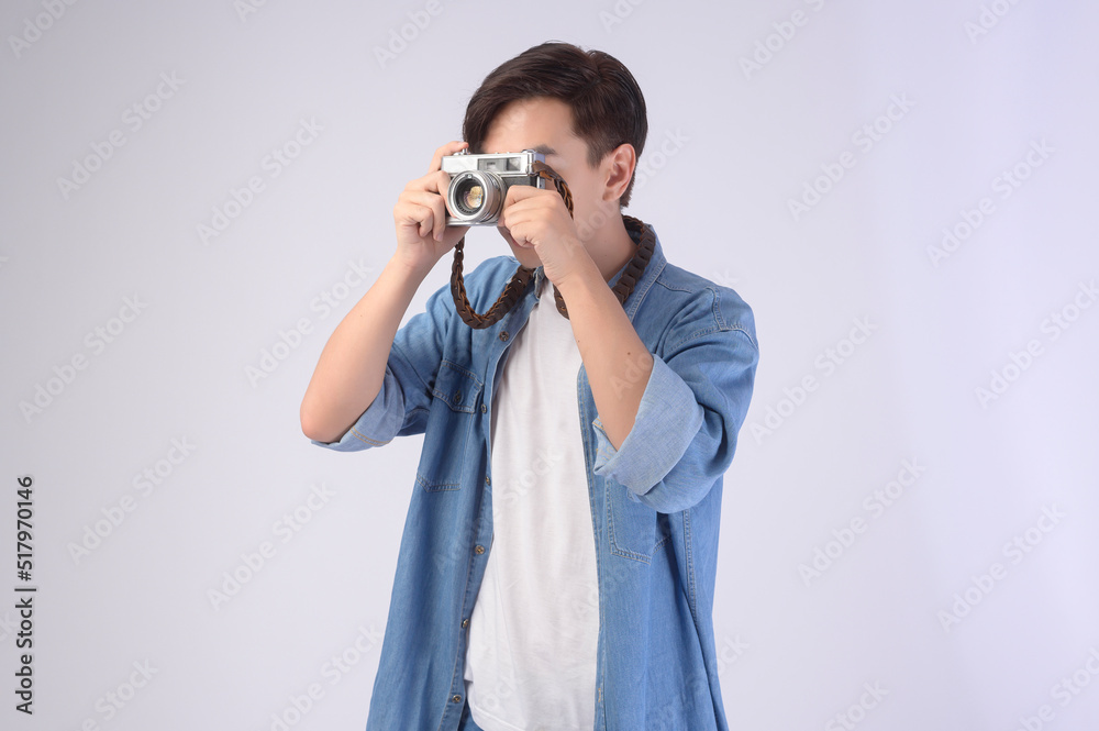 Young happy asian tourist man over white background studio, travel and holidays concept.