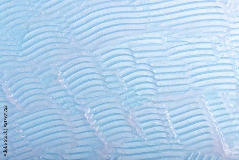 Fototapeta premium Abstract patterns of transparent moisturizing facial gel. The texture of the cosmetic product is smeared on a blue background.