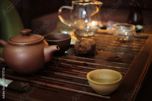 Traditional chinese tea ceremony utensils on a tea tray. Chinese teapots made of brown yixing clay and glass and cups. Tea brewing equipment low key dark mood