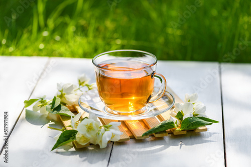Jasmine tea in glass cup and flowers on a wooden white background, natural light photo. Cup with green jasmin tea