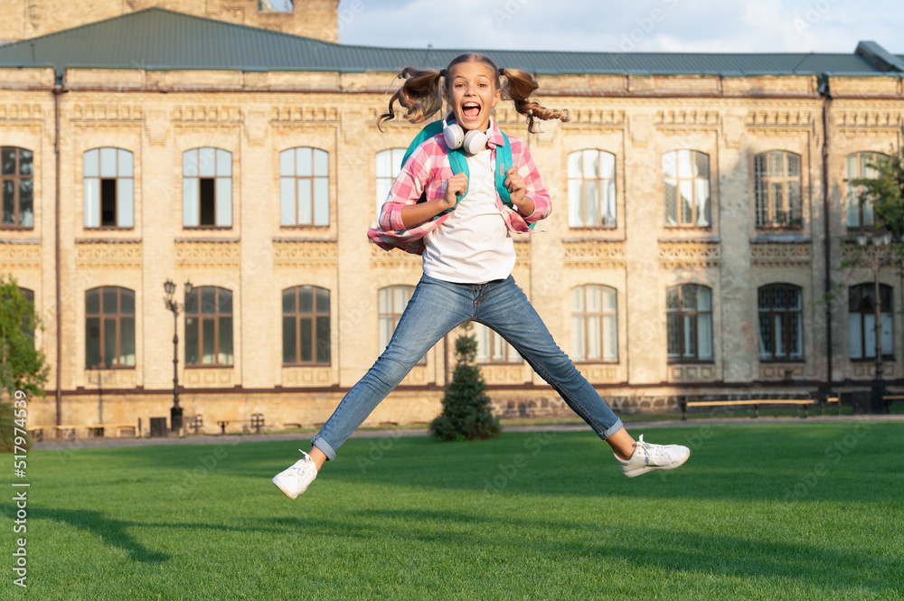 Fototapeta premium Happy active teen girl jumping in school yard outdoors, September 1.