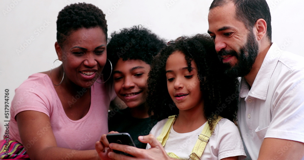 Obraz premium Interracial family using cellphone. Mixed race parents and children looking at smartphone device