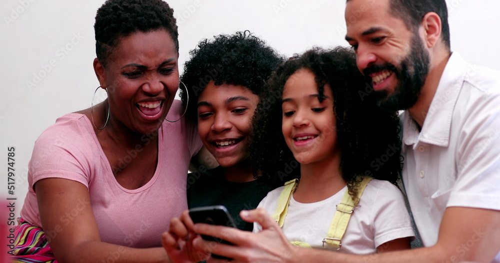 Obraz premium Interracial family using cellphone. Mixed race parents and children looking at smartphone device