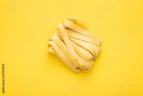 Uncooked pappardelle pasta on yellow background. photo