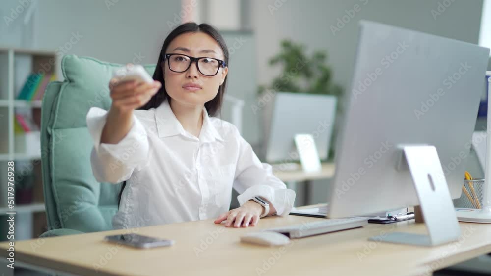 Woman employee entrepreneur. office worker Turn on a remote control air conditioner, cooling system or humidifier. business Female Sitting at work at a computer desk. Workplace, changing temperature Woman employee entrepreneur. office worker Turn on a remote control air conditioner, cooling system or humidifier. business Female Sitting at work at a computer desk. Workplace, changing temperature