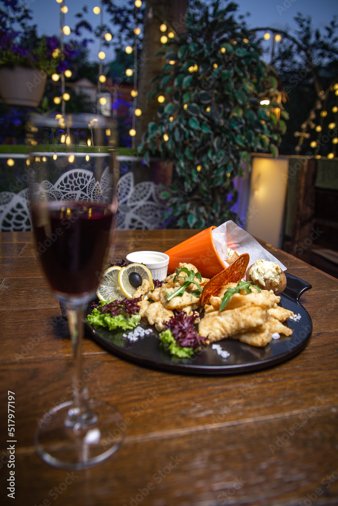appetizer in batter with potatoes on a black plate with wine appetizer in batter with potatoes on a black plate with wine