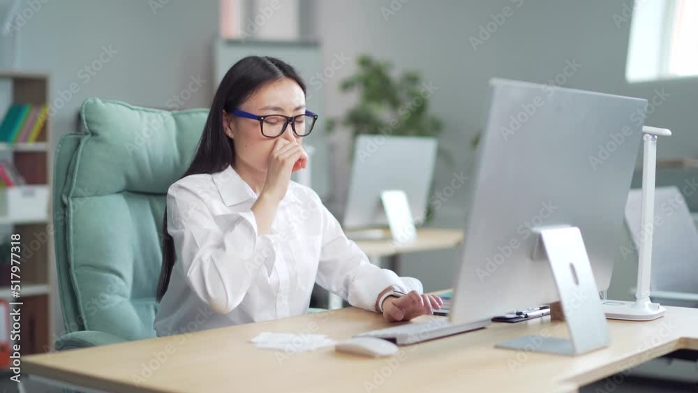 employee suffers from allergies in the office. Young worker sneezes at workplace. Sick female with runny nose with handkerchief indoors Allergen. Business woman is sick with allergy allergic reaction employee suffers from allergies in the office. Young worker sneezes at workplace. Sick female with runny nose with handkerchief indoors Allergen. Business woman is sick with allergy allergic reaction