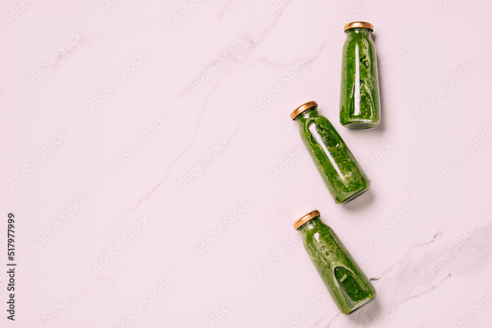 Green vegetable fruit smoothie, drink bottles, light marbled background. Vegetarianism proper diet Green vegetable fruit smoothie, drink bottles, light marbled background. Vegetarianism proper diet