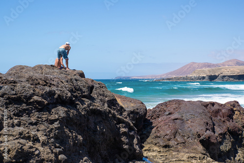 Rear View of Two Man on a Rock Watching the Waves in Playa de Garcey,Fuerteventura,Canary Island © nicolas