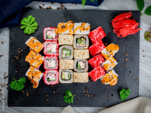 Set with fried and baked rolls, sushi on a stone board on a light table