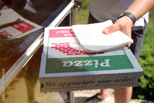 Delivery man is giving pizza to customer on the doorstep.