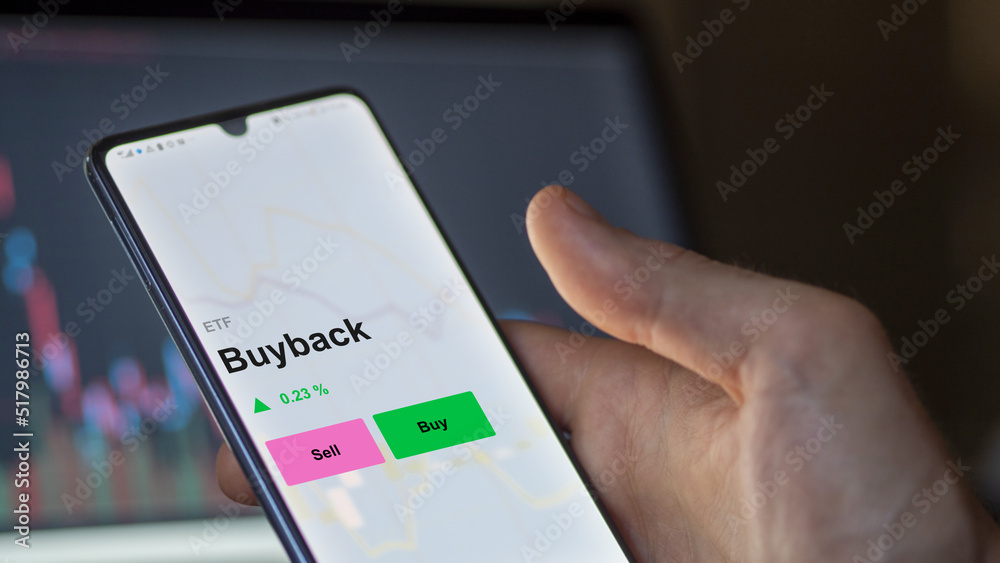 An investor's analizing the buyback etf fund on a screen. A phone shows the prices of Buyback An investor's analizing the buyback etf fund on a screen. A phone shows the prices of Buyback
