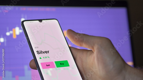 An investor's analizing the silver etf fund on a screen. A phone shows the prices of Silver