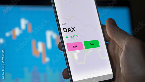 An investor's analizing the dax etf fund on a screen. A phone shows the prices of DAX