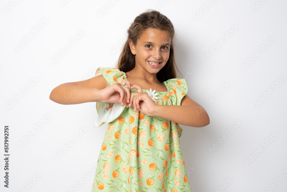 Cute smiling brunette child girl heart figure with fingers standing isolated over white background. Cute smiling brunette child girl heart figure with fingers standing isolated over white background.