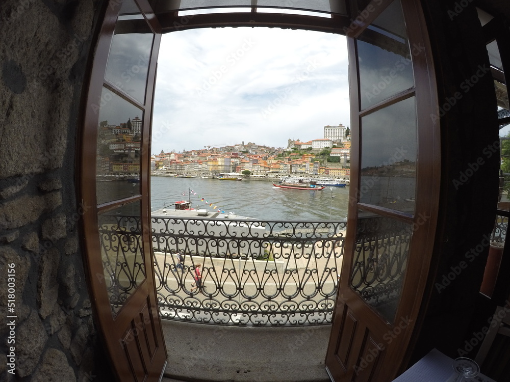 View of a river with boats through an old window door.In the background you can see a small town.  