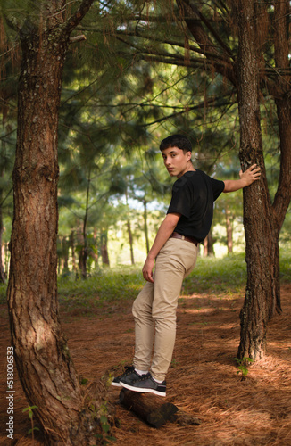 Young man with natural style standing in the middle of the pine tree forest