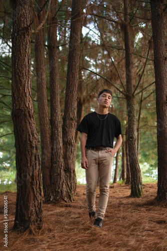 Young man with natural style walking in the middle of the pine tree forest