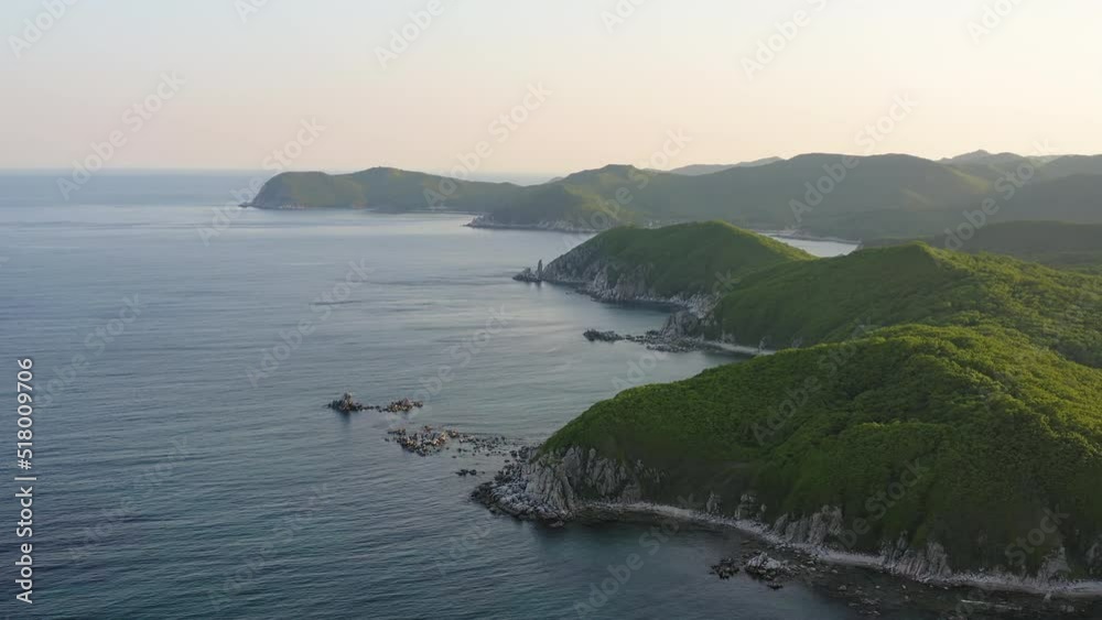 Cinematic shot of endless mountains and forests on the coast of the Sea of Japan at sunset. The concept of summer holidays in the wild. Drone view Cinematic shot of endless mountains and forests on the coast of the Sea of Japan at sunset. The concept of summer holidays in the wild. Drone view