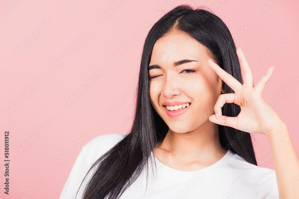 Portrait Asian beautiful young woman made finger OK symbol sign gesture wink eyes to agree and looking at camera, studio shot isolated on pink background, Thai female agree hand sign copy space Portrait Asian beautiful young woman made finger OK symbol sign gesture wink eyes to agree and looking at camera, studio shot isolated on pink background, Thai female agree hand sign copy space