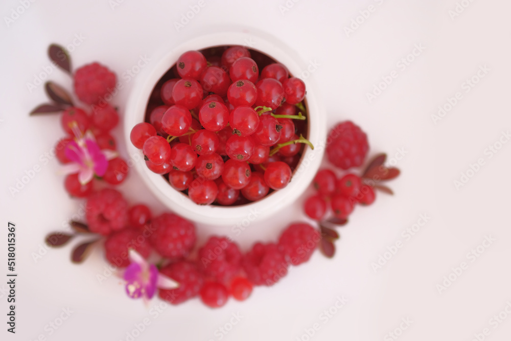 Red currants in a white cup and raspberries on a white background. Red currants in a white cup and raspberries on a white background.