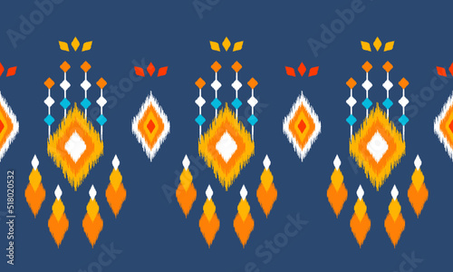 Ikat ethnic background vector. Seamless pattern in white, orange, blue square shapes decorated with colorful tassels and flower petals on dark blue background.