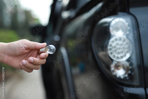 Man mechanic changing car's tail lamp in hand on car taillight background . Repairing car.