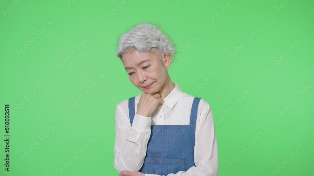 悩むエプロンをつけたシニア女性 クロマキー合成用グリーンバック 悩むエプロンをつけたシニア女性 クロマキー合成用グリーンバック