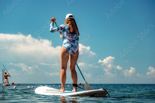 Woman sup sea. Happy healthy fit woman in bikini relaxing on a sup surfboard, floating on the clear turquoise sea water. Recreational Sports. Stand Up Paddle boarding. Summer fun, holidays travel.