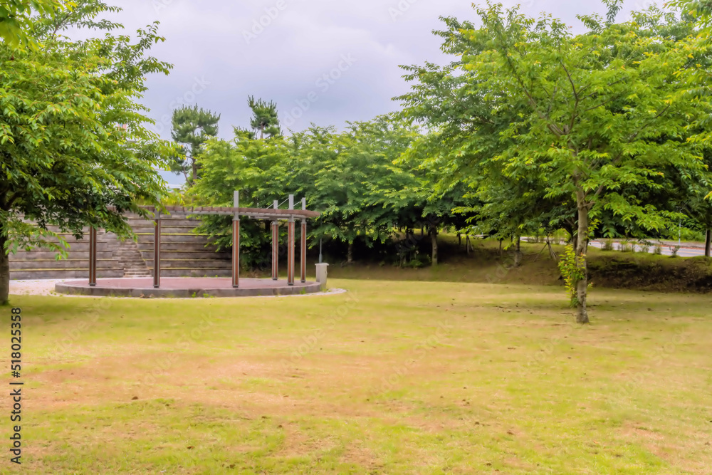 Round wooden stage in rural park on cloudy day.