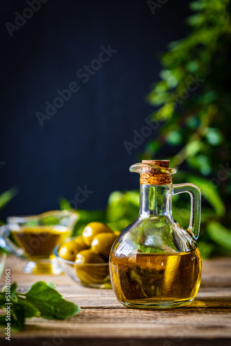 Green olives fruits in olive oil on wooden table 