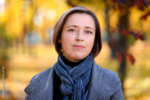 portrait of a beautiful woman posing in a city park in autumn, bright sunny day, colorful yellow leaves © soleg