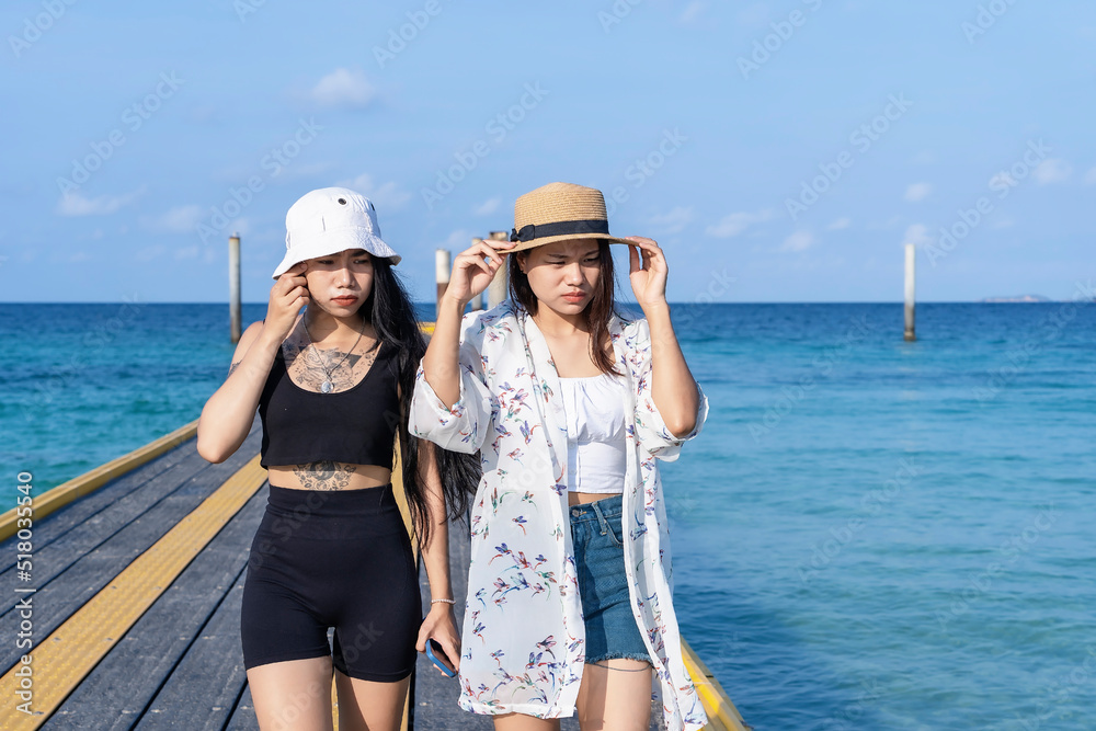 Two women friends or couples relaxing in the sea and walking at tropical beach travel summer holidays. Female tourists enjoy traveling to exotic nature in their leisure time. Friendship concept