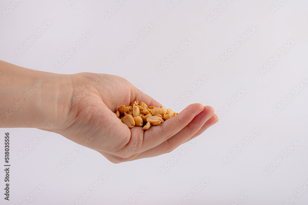 Hand holding heap of salt roasted peanuts on white background Hand holding heap of salt roasted peanuts on white background