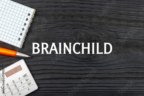BRAINCHILD - word (text) on a dark wooden background, notepad. Business concept (copy space).