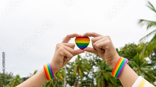 Lesbian gay woman trust hand symbol of love outdoors. LGBT Coupple trust hand make love outdoors. LGBTQ show Rainbow Wristband photo