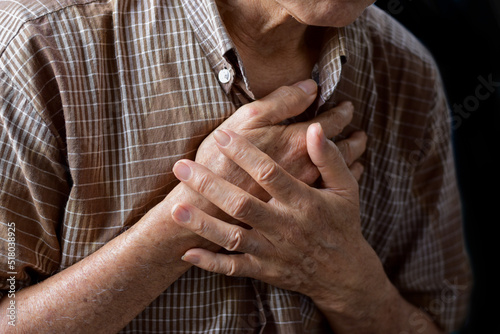 Asian man suffering from central chest pain. Chest pain can be caused by heart attack, myocardial infarct or ischemia, myocarditis, pneumonia, stress, etc,.