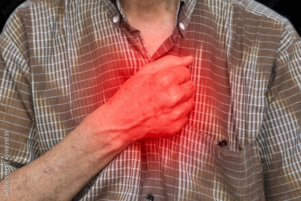 Asian man suffering from central chest pain. Chest pain can be caused