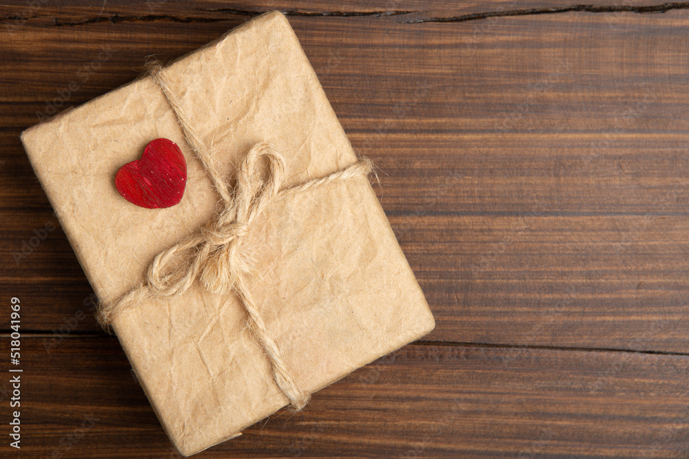 Valentine's Day greetings concept. Little red wooden crafted heart and gift box close up on the wooden background. Valentines greeting card. Valentine's Day greetings concept. Little red wooden crafted heart and gift box close up on the wooden background. Valentines greeting card.