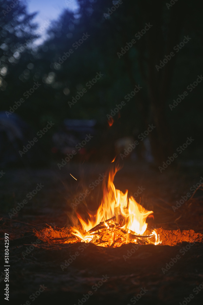 Beautiful campfire in the evening at the forest. Fire burning in dusk at campsite near a river in beautiful nature with evening sky at background Beautiful campfire in the evening at the forest. Fire burning in dusk at campsite near a river in beautiful nature with evening sky at background