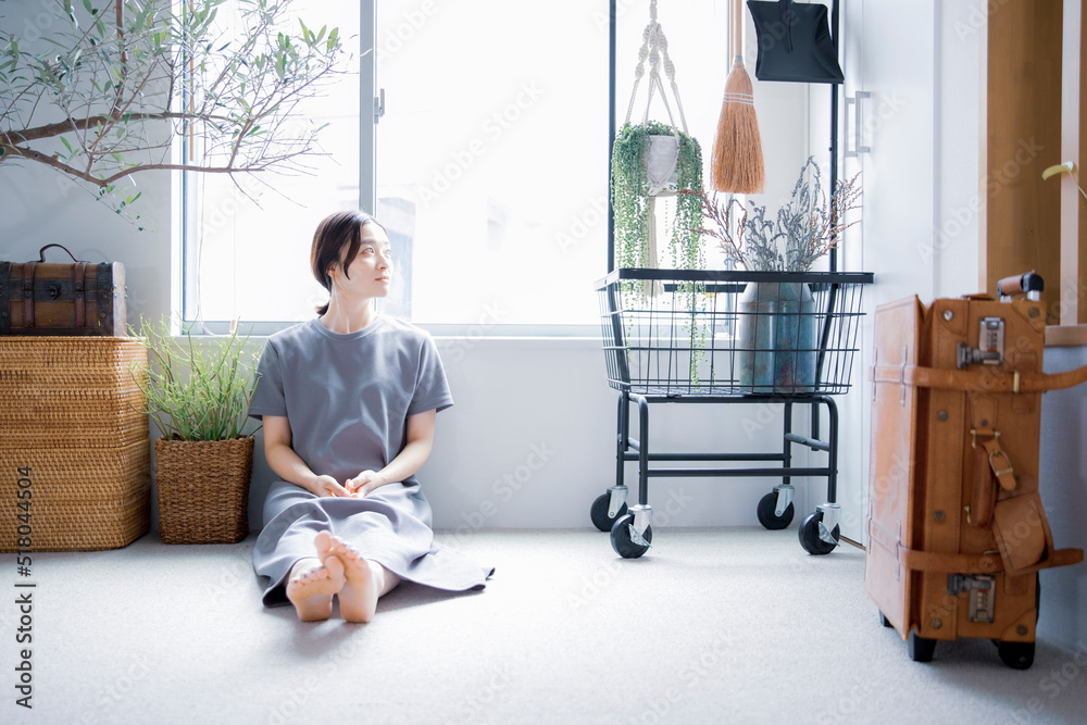 明るい植物のある窓辺の部屋で座って空を見上げて休憩する日本人女性 明るい植物のある窓辺の部屋で座って空を見上げて休憩する日本人女性