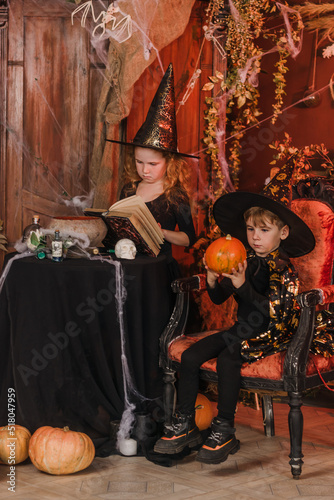 Little boy and girl in a black witch costumes and hats in a Halloween decorations.Halloween concept.Selective focus.