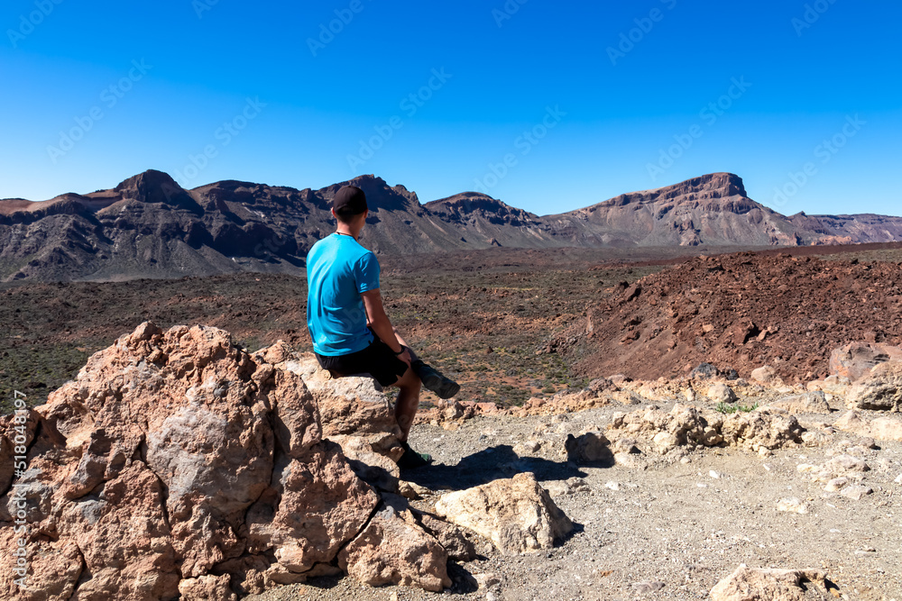 Man sitting on rock with scenic view on mount Guajara, Roque de la Grieta in volcano Mount Teide National Park, Tenerife, Canary Islands, Spain, Europe. Volcanic landscape. View from Minas de San Jose