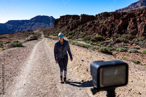 Filming with action camera of woman walking on scenic hiking trail leading to Guajara, Roque de la Grieta near Montana Majua, volcano Mount Teide National Park, Tenerife, Canary Islands, Spain, Europe