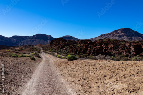 Scenic hiking trail leading to Guajara, Roque de la Grieta near Montana Majua in volcano Mount Teide National Park, Tenerife, Canary Islands, Spain, Europe. Volcanic barren desert landscape. Dirt road