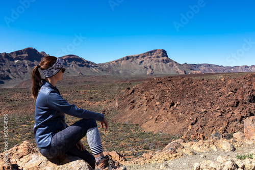 Woman sitting on rock with scenic view on Guajara, Roque de la Grieta in volcano Mount Teide National Park, Tenerife, Canary Islands, Spain, Europe. Volcanic landscape. View from Minas de San Jose photo