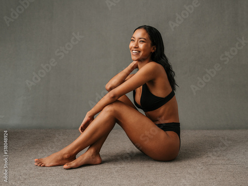Lovely smiling African American female sitting and showing her well toned body