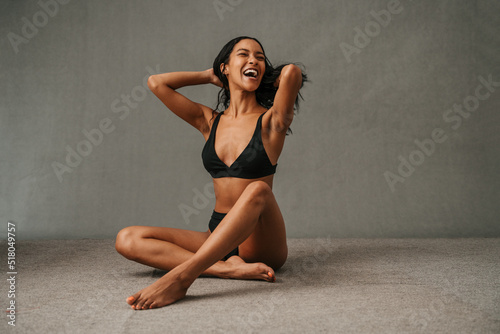 Attractive Multiethnic female sitting bare foot on the studio floor