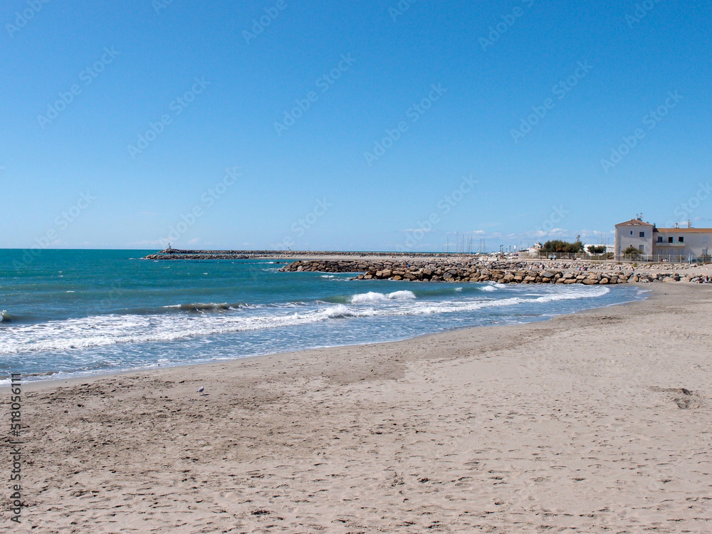 View of an empty sandy beach with rocks and stones under the blue sky