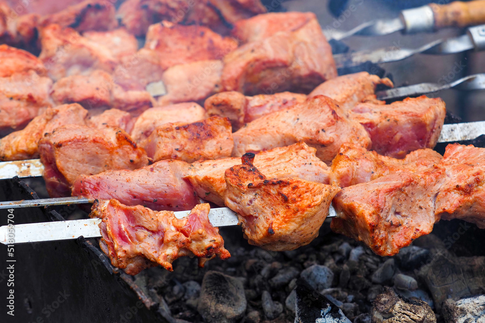 Close-up of meat on barbecue grill with smoke. Delicious grilled meat in BBQ. Barbecue, kebabs on the grill
